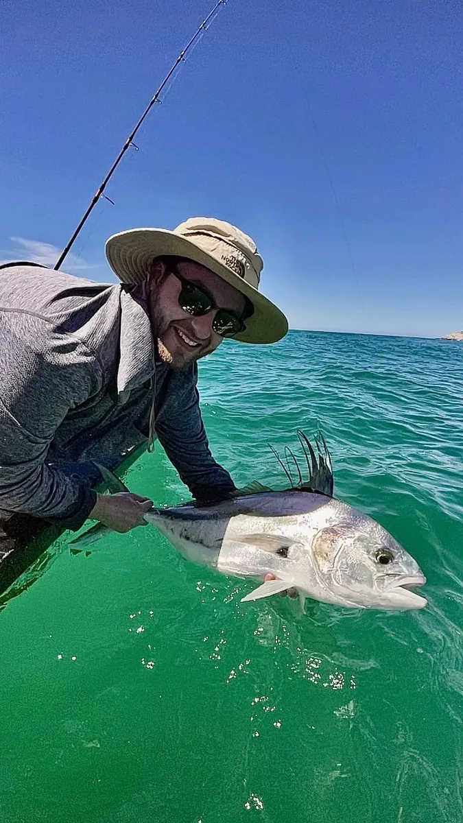 Pescador liberando un pez gallo en el agua turquesa del Pacífico mexicano